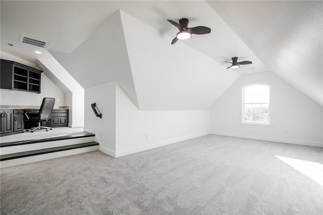 bonus room with ceiling fan, built in desk, light carpet, and vaulted ceiling