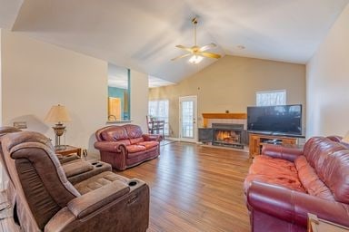 living room with ceiling fan, vaulted ceiling, and light hardwood / wood-style flooring