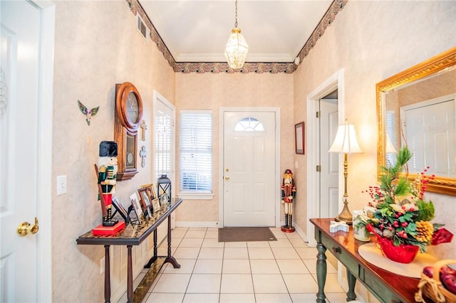 entryway with crown molding and light tile patterned floors