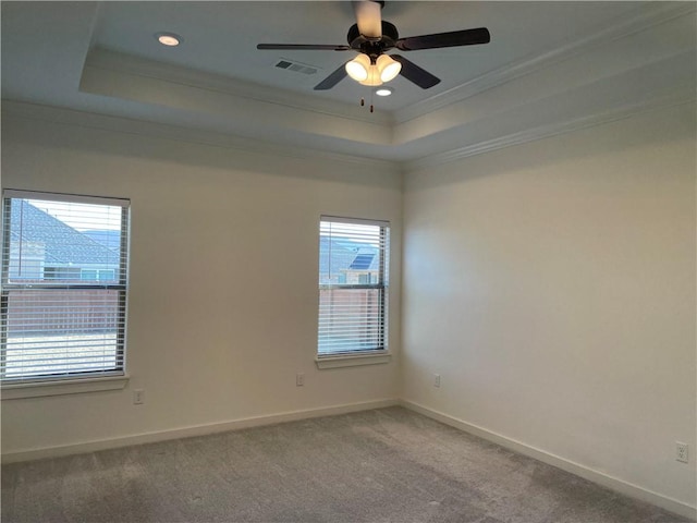 carpeted empty room with ceiling fan, a raised ceiling, and crown molding