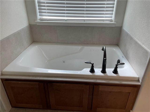 bathroom with a textured wall and a tub with jets