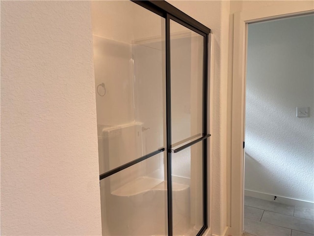 full bathroom with a shower stall, baseboards, and a textured wall