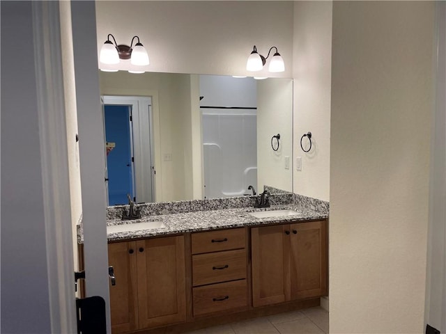 full bath featuring double vanity, tile patterned flooring, walk in shower, and a sink