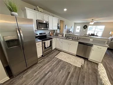 kitchen featuring white cabinets, dark hardwood / wood-style floors, kitchen peninsula, and appliances with stainless steel finishes