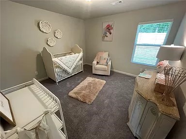 bedroom featuring a nursery area and dark carpet