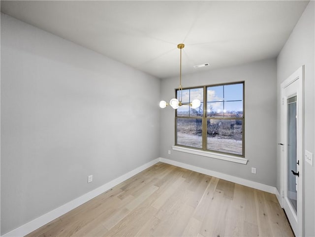 unfurnished dining area featuring a notable chandelier and light hardwood / wood-style floors