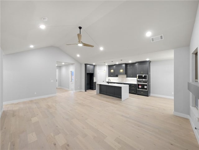 unfurnished living room featuring sink, light hardwood / wood-style flooring, ceiling fan, and vaulted ceiling