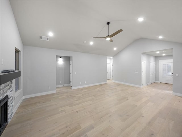 unfurnished living room with ceiling fan, lofted ceiling, a fireplace, and light wood-type flooring