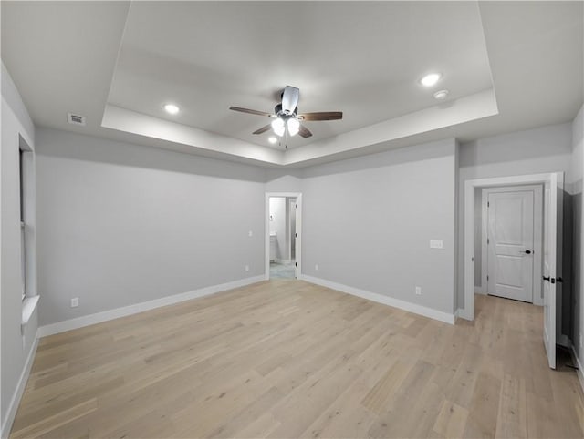 interior space featuring light hardwood / wood-style flooring, a raised ceiling, and ceiling fan