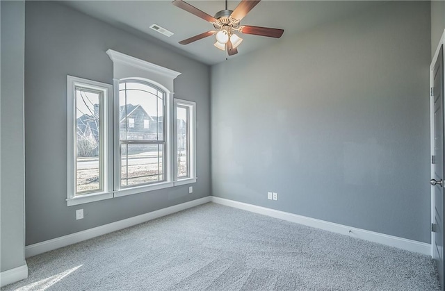 carpeted spare room featuring a wealth of natural light and ceiling fan