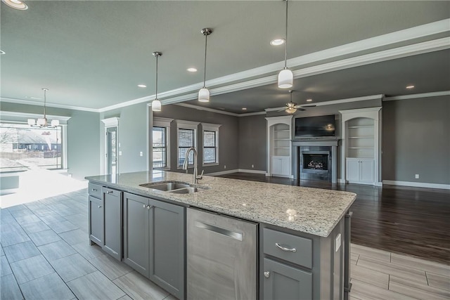 kitchen featuring pendant lighting, a kitchen island with sink, sink, stainless steel dishwasher, and light wood-type flooring