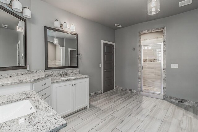 bathroom featuring a shower with door and vanity