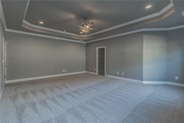 unfurnished room featuring a raised ceiling, ceiling fan, carpet, and ornamental molding