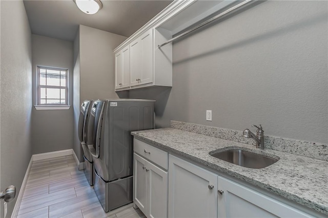 clothes washing area featuring cabinets, light wood-type flooring, sink, and washing machine and dryer