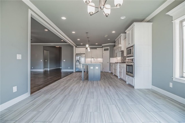 kitchen with appliances with stainless steel finishes, light wood-type flooring, pendant lighting, a center island with sink, and white cabinets