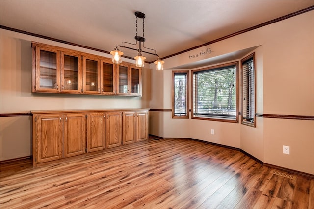 interior space with an inviting chandelier, decorative light fixtures, crown molding, and light hardwood / wood-style floors