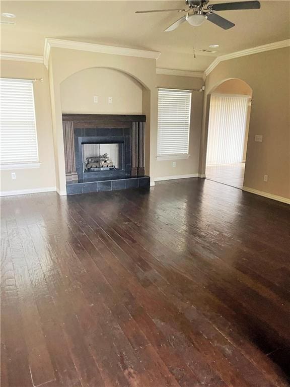 unfurnished living room with a tile fireplace, ceiling fan, dark hardwood / wood-style floors, and ornamental molding