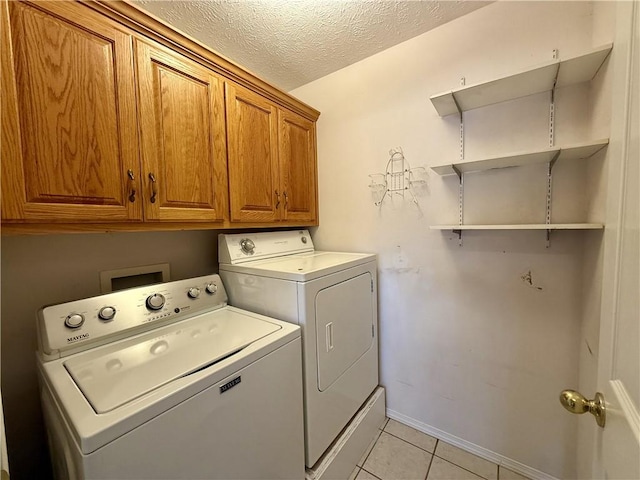 laundry room featuring separate washer and dryer, light tile patterned floors, cabinets, and a textured ceiling