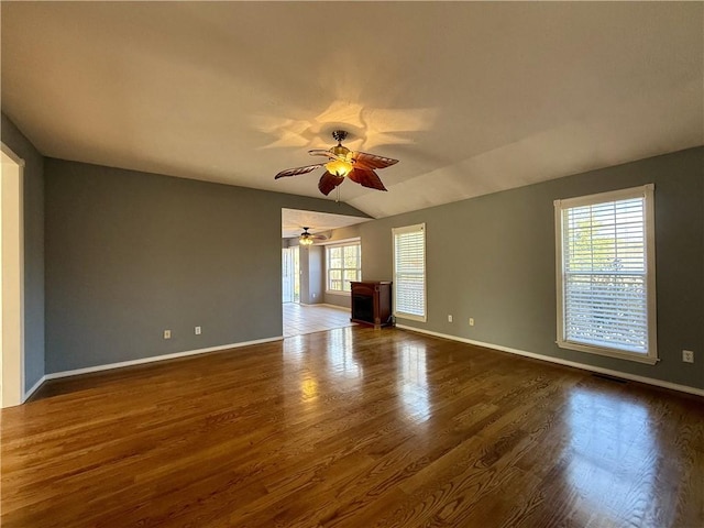 empty room with lofted ceiling, ceiling fan, and dark wood-type flooring