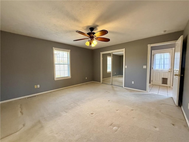 unfurnished bedroom with a textured ceiling, ceiling fan, and light carpet