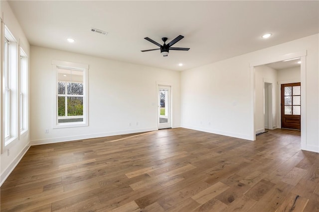 unfurnished room with a healthy amount of sunlight, visible vents, and wood finished floors