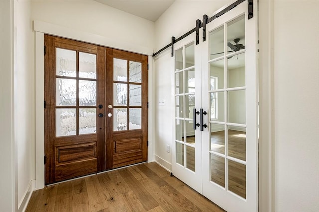 doorway with french doors, a barn door, and wood finished floors