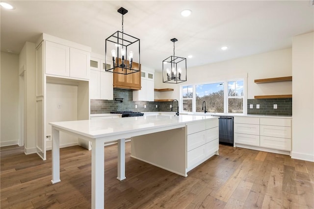 kitchen with wood finished floors, white cabinetry, light countertops, dishwasher, and open shelves