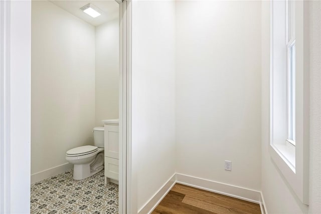 bathroom with wood finished floors, toilet, and baseboards