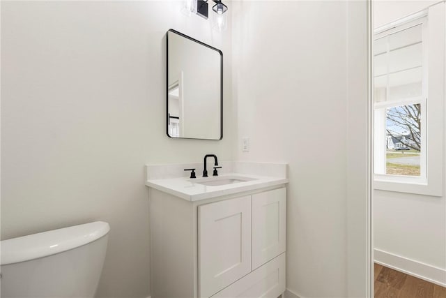 bathroom featuring toilet, wood finished floors, vanity, and baseboards