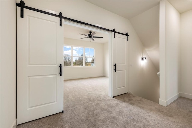 bonus room with a barn door, carpet, a ceiling fan, and baseboards