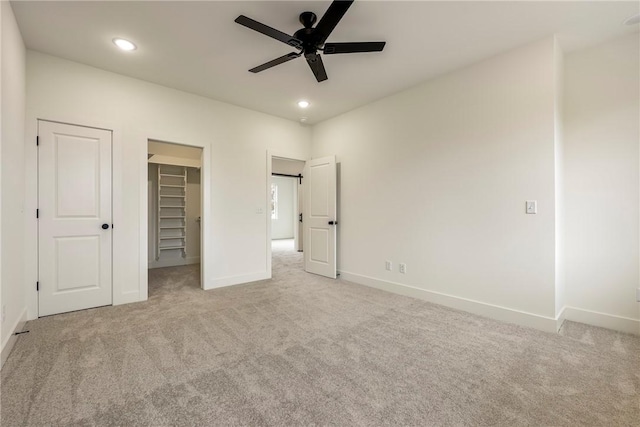 unfurnished bedroom with baseboards, a walk in closet, carpet flooring, and recessed lighting