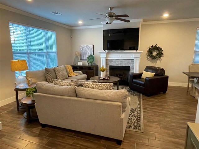 living room with crown molding, ceiling fan, a fireplace, and dark wood-type flooring