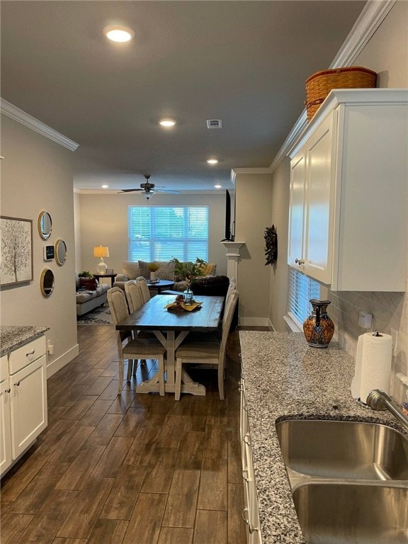 dining space with ornamental molding, sink, and dark hardwood / wood-style flooring