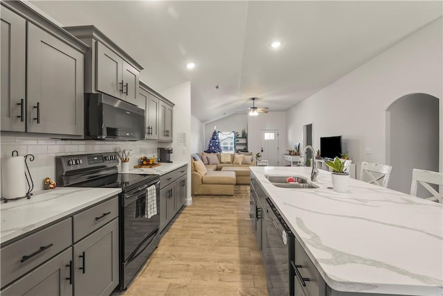 kitchen with decorative backsplash, appliances with stainless steel finishes, sink, light hardwood / wood-style flooring, and lofted ceiling