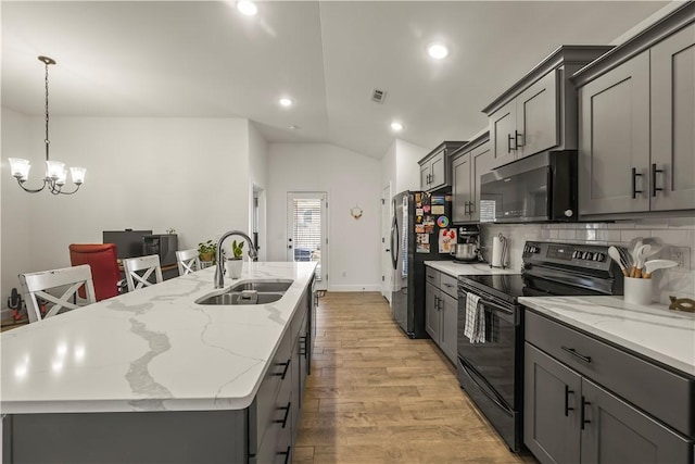 kitchen featuring sink, stainless steel appliances, a chandelier, vaulted ceiling, and light wood-type flooring