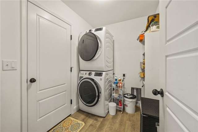 clothes washing area with stacked washer and dryer and light wood-type flooring