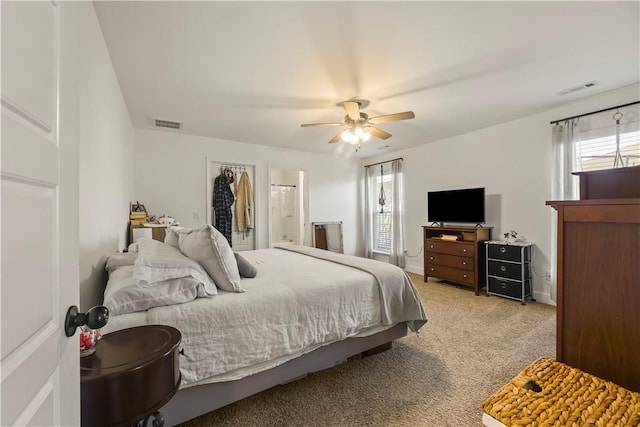 carpeted bedroom featuring ceiling fan, a walk in closet, and a closet