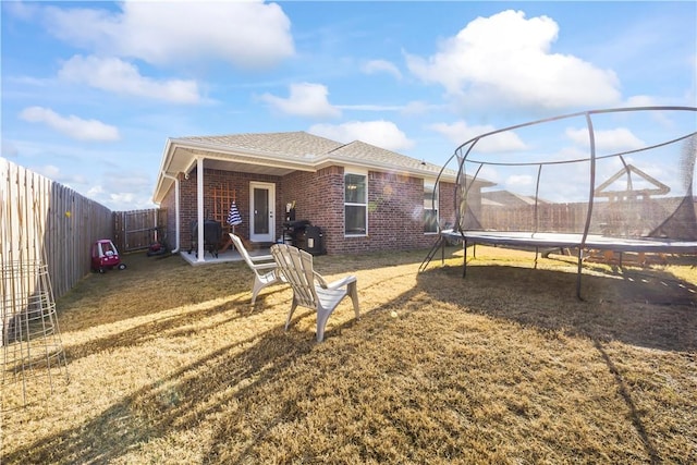 rear view of property with a lawn and a trampoline