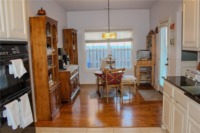 kitchen with light hardwood / wood-style floors, hanging light fixtures, and black double oven