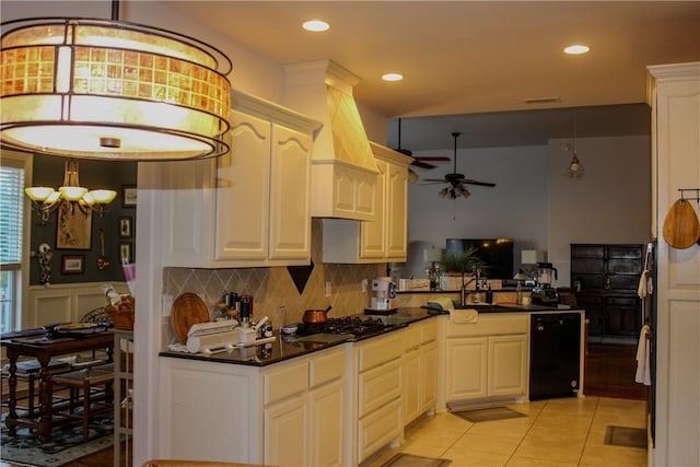 kitchen featuring black dishwasher, pendant lighting, stainless steel gas stovetop, light tile patterned floors, and ceiling fan with notable chandelier