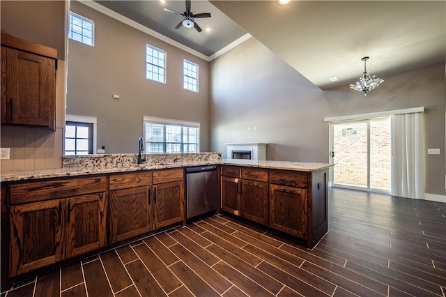 kitchen with stainless steel dishwasher, kitchen peninsula, a towering ceiling, ceiling fan with notable chandelier, and ornamental molding