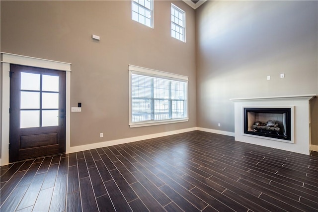 unfurnished living room featuring plenty of natural light and a high ceiling