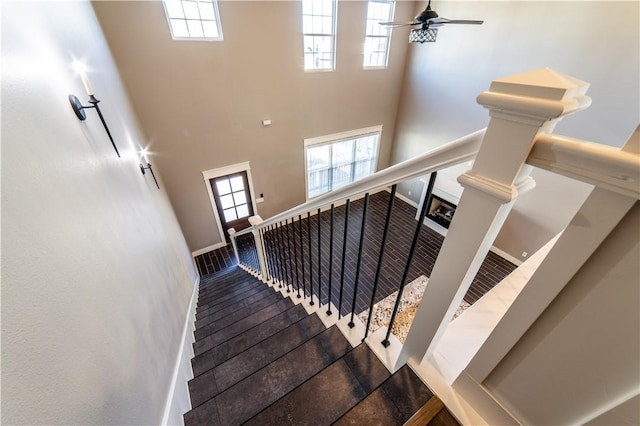 stairs with ceiling fan, hardwood / wood-style floors, and a towering ceiling