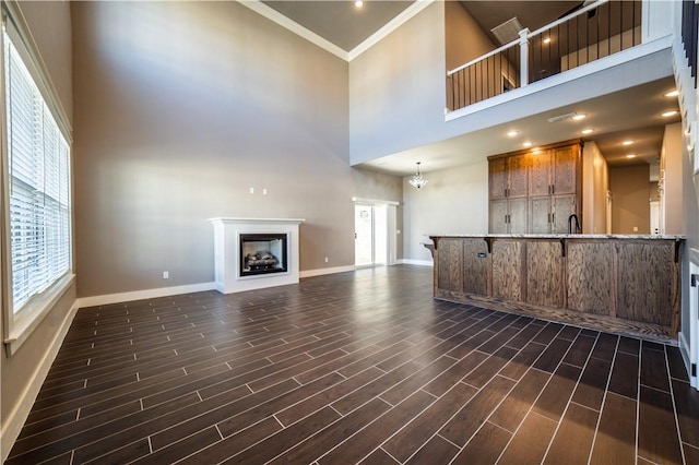 unfurnished living room with crown molding, a high ceiling, and a notable chandelier