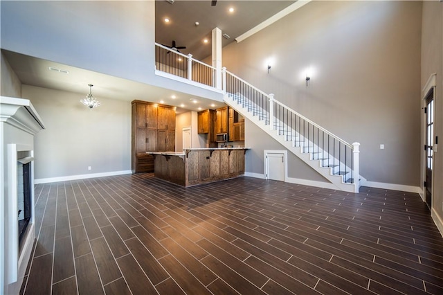 unfurnished living room featuring ceiling fan with notable chandelier and a high ceiling