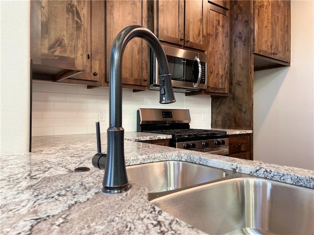 kitchen with appliances with stainless steel finishes, backsplash, and light stone counters