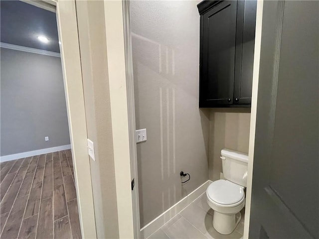 bathroom with ornamental molding, wood-type flooring, and toilet