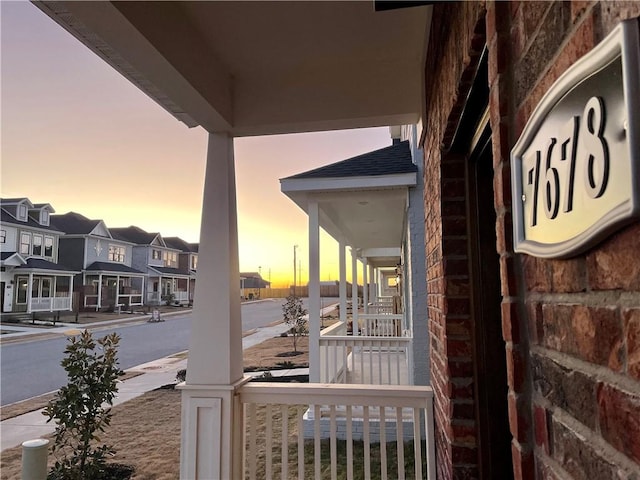 balcony at dusk featuring covered porch