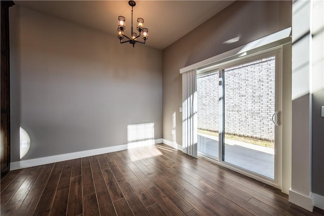 spare room featuring dark hardwood / wood-style floors and a notable chandelier