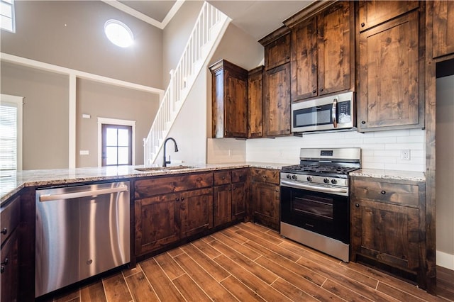 kitchen featuring backsplash, dark wood-type flooring, sink, light stone countertops, and stainless steel appliances